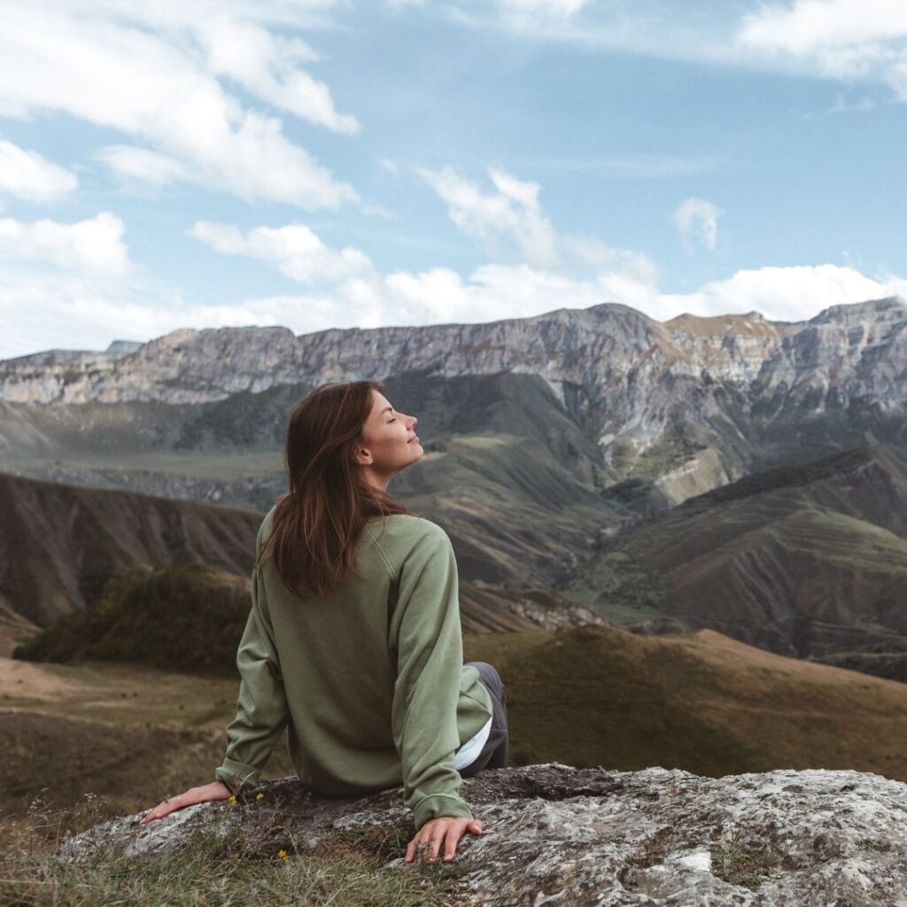 smiling woman sitting on hike taking a deep breath